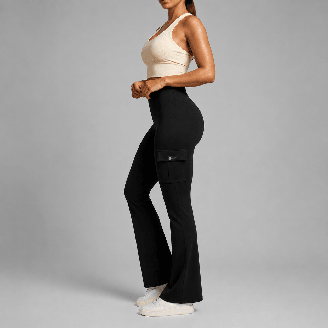 Person wearing black cargo pants and a beige top on a gray background