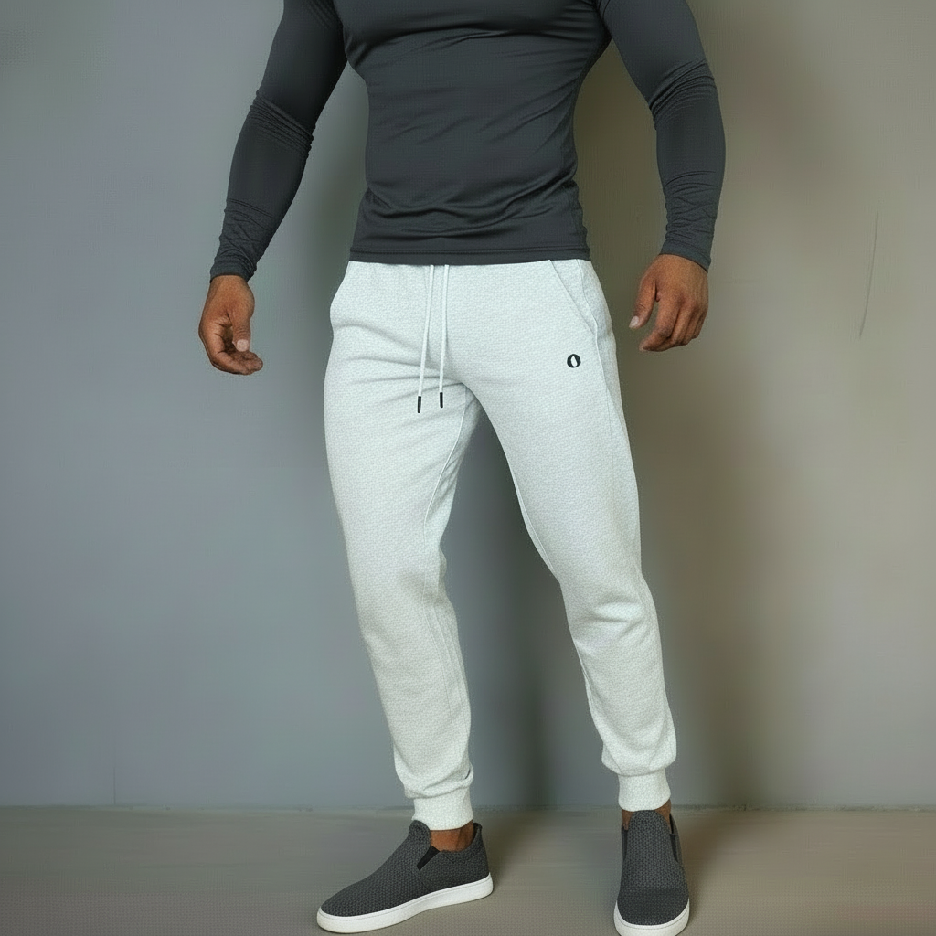 Person wearing a white long-sleeve top and light gray sweatpants with a logo, standing against a plain background.