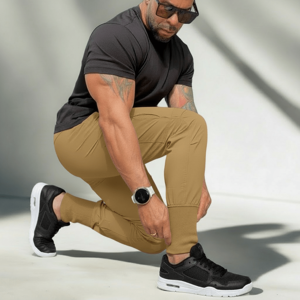 Man wearing black t-shirt, beige pants, and black sneakers on a neutral background