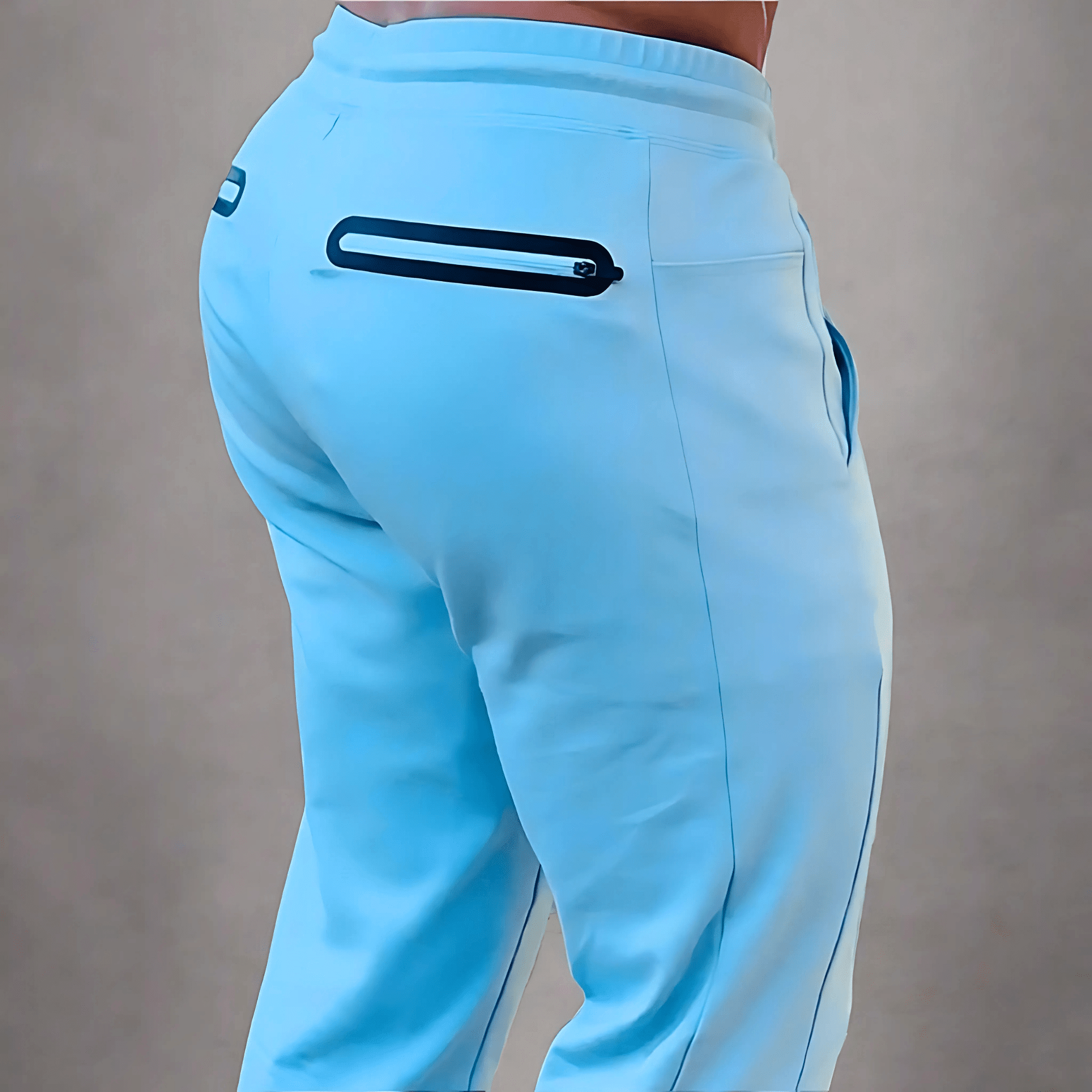 Light blue athletic pants shown from the back on a model, featuring a zippered pocket and a small black logo near the waistband.