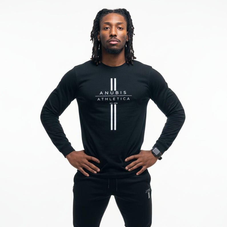 Person wearing a black long-sleeve shirt with a logo and black pants on a gray background