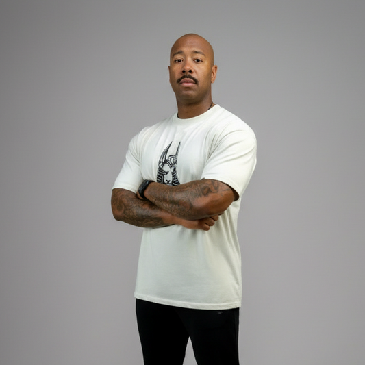 Man wearing a white t-shirt with a graphic design, black pants, and white sneakers on a gray background