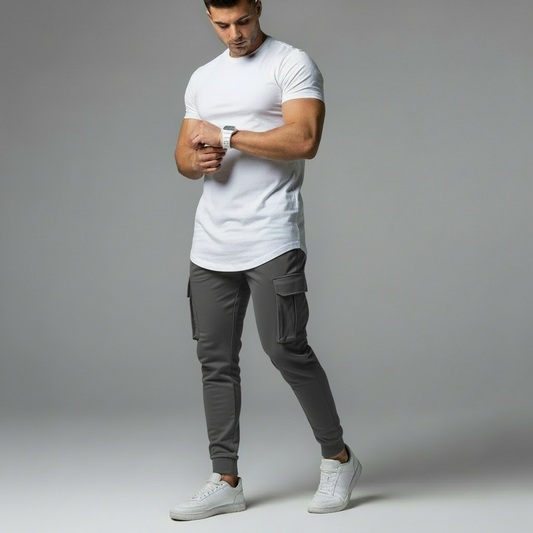 Man wearing a white t-shirt and dark cargo pants on a gray background