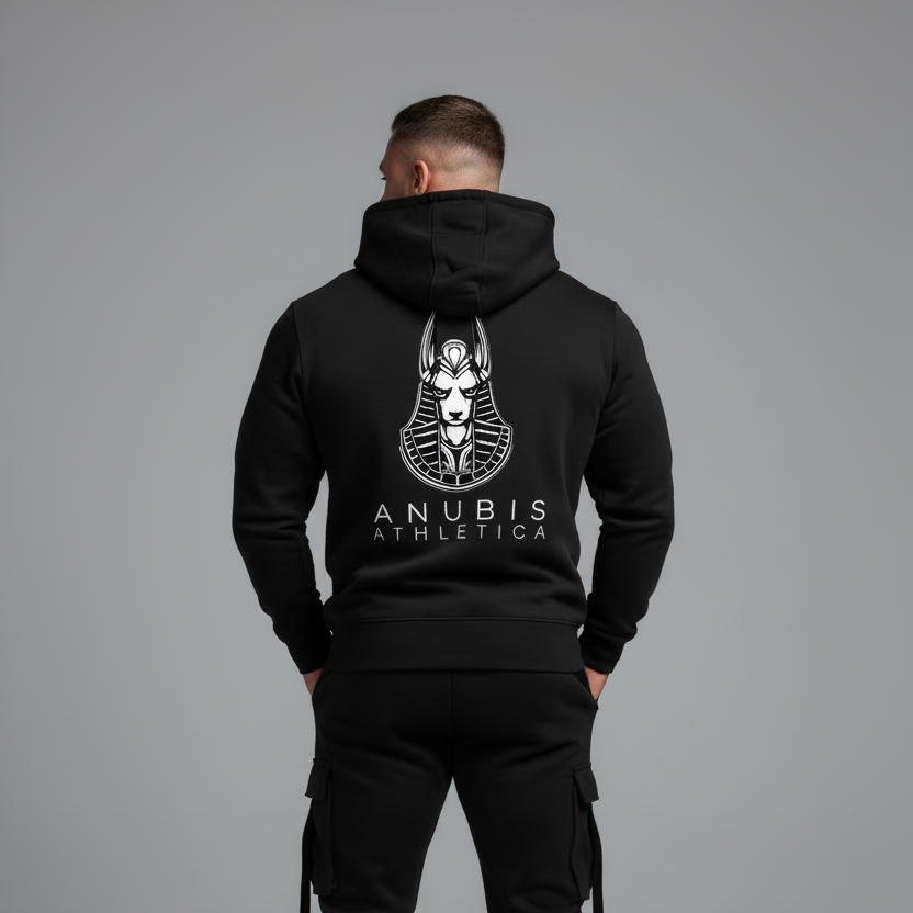 Person wearing a black hoodie with 'Anubis Athletics' logo on the back, standing against a gray background.