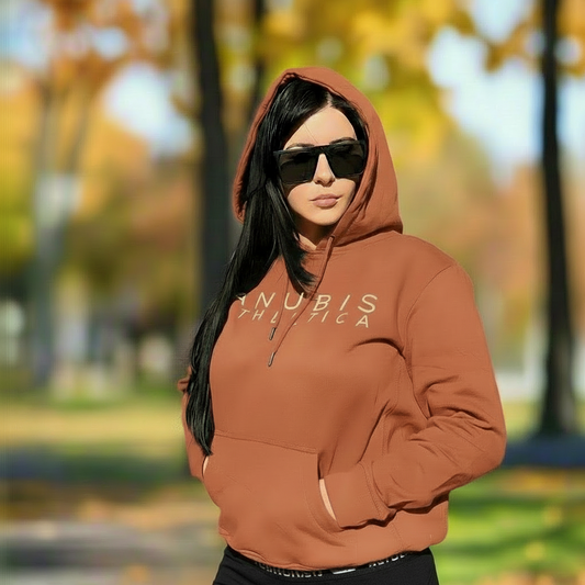 Person wearing a brown hoodie with 'ANUBIS ATHLETICA' text in an outdoor setting with trees and grass.