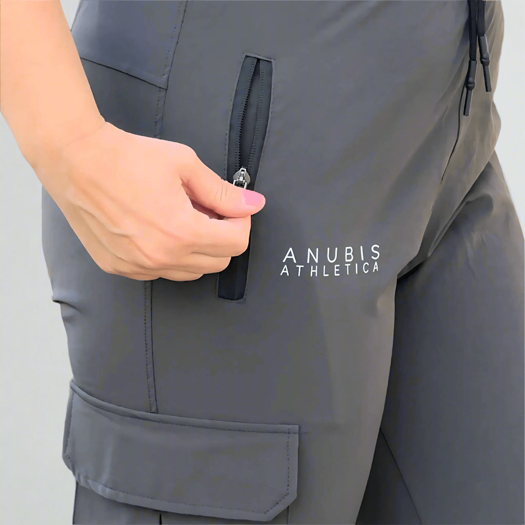 Person zipping a gray athletic outfit with 'Anubis Athletica' branding.