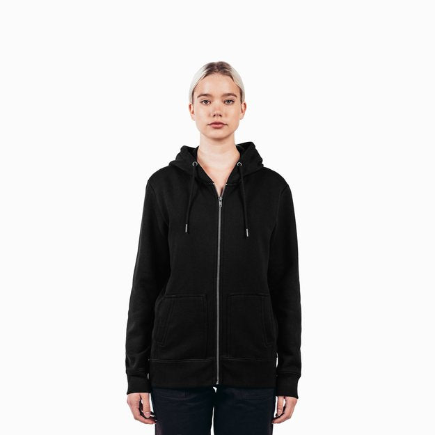 a Caucasian female model wearing a black zip up hoodie and matching pants in front of a white background