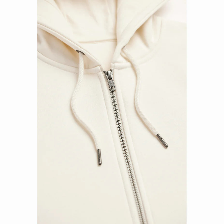 close up view of a cream colored hoodie showing the upper zipper and drawstrings