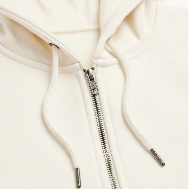 close up view of a cream colored hoodie showing the upper zipper and drawstrings