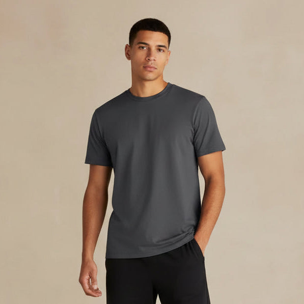 Person wearing a plain dark gray t-shirt against a beige background