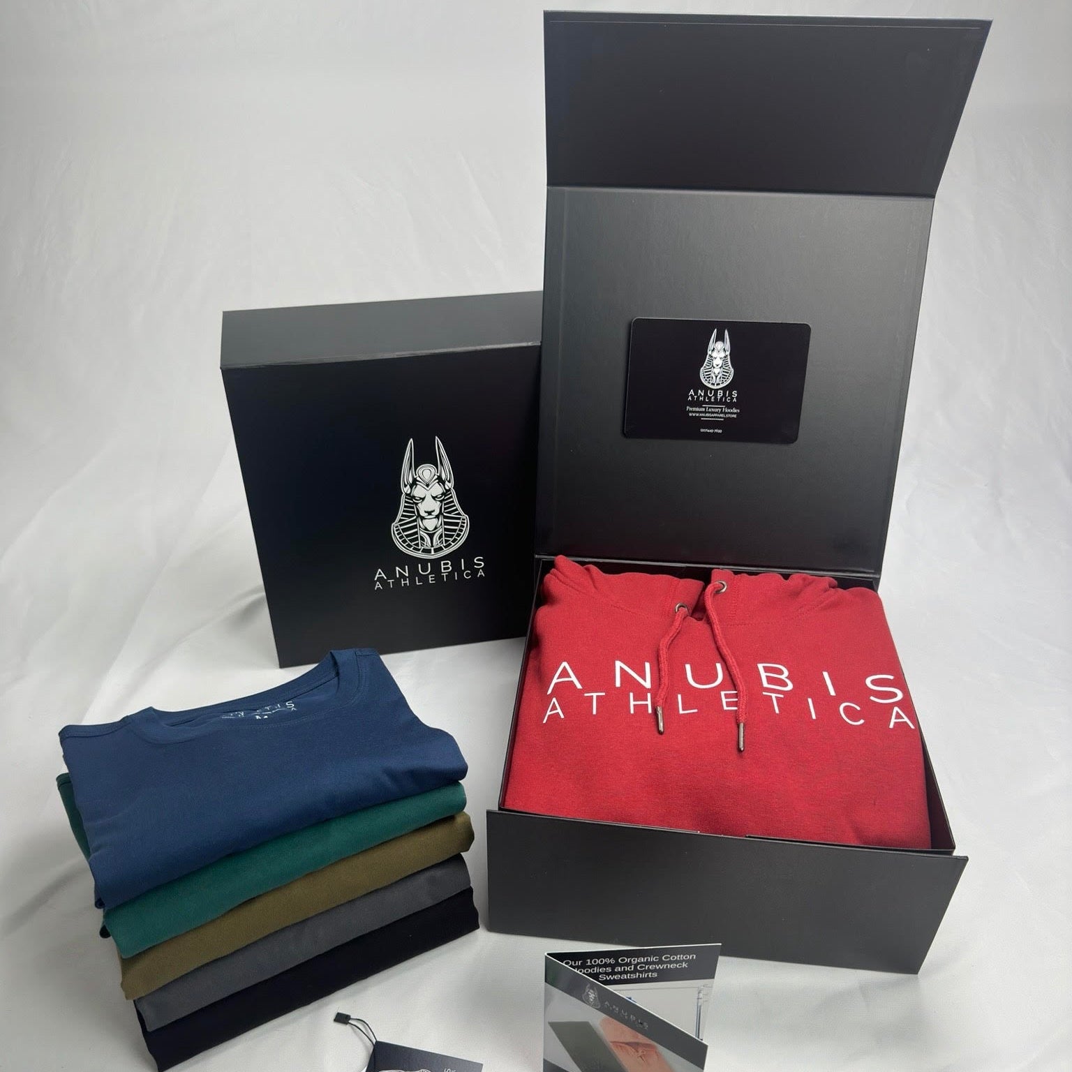 A photo showing a display of the tee shirts and packaging provided to customers that buy the white crown collection, this includes a custom box, thank you card, and custom hangtags