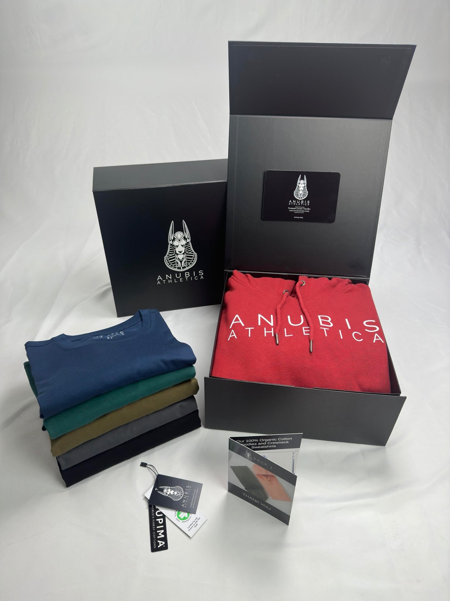 A photo showing a display of the tee shirts and packaging provided to customers that buy the white crown collection, this includes a custom box, thank you card, and custom hangtags