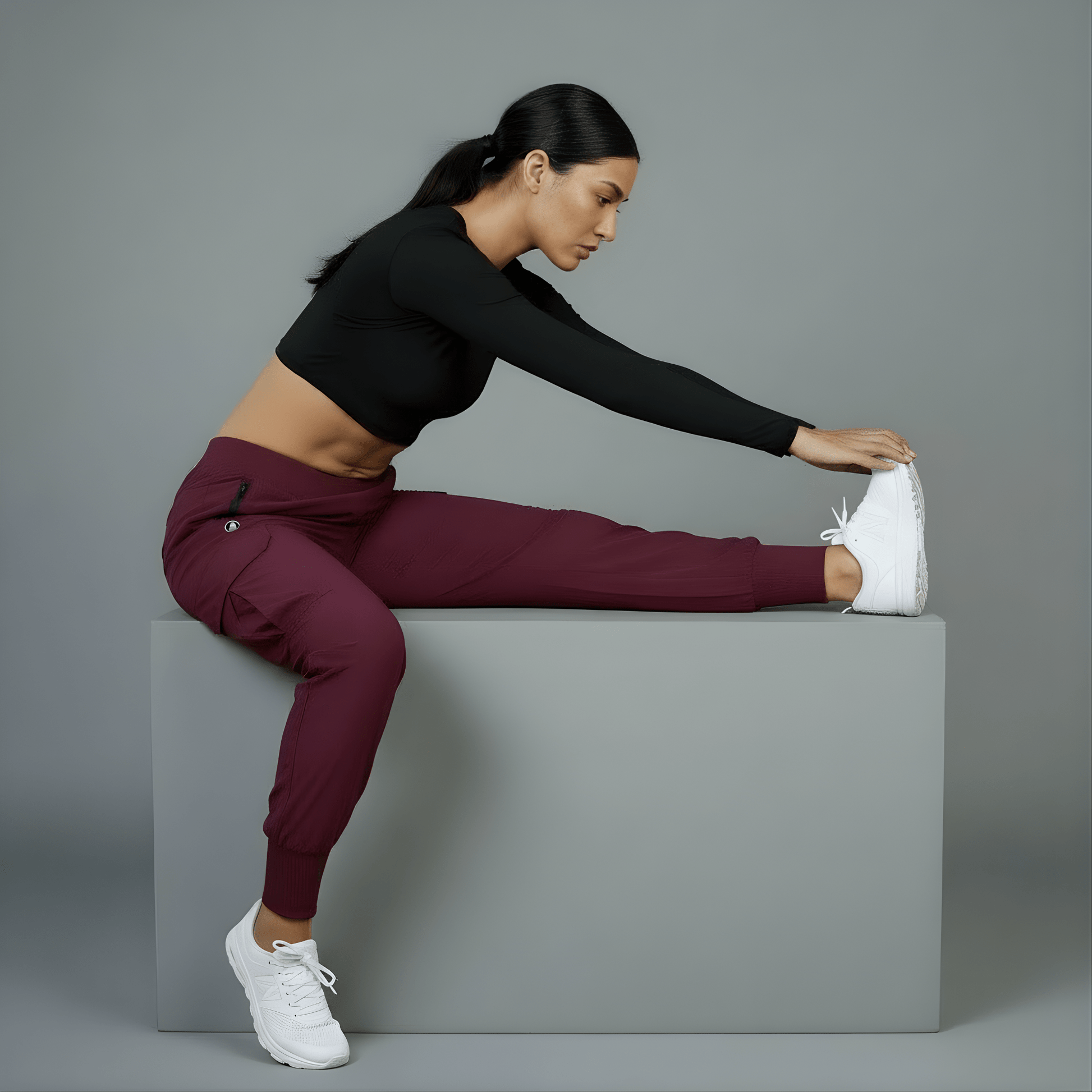 Woman stretching on a gray block against a gray background