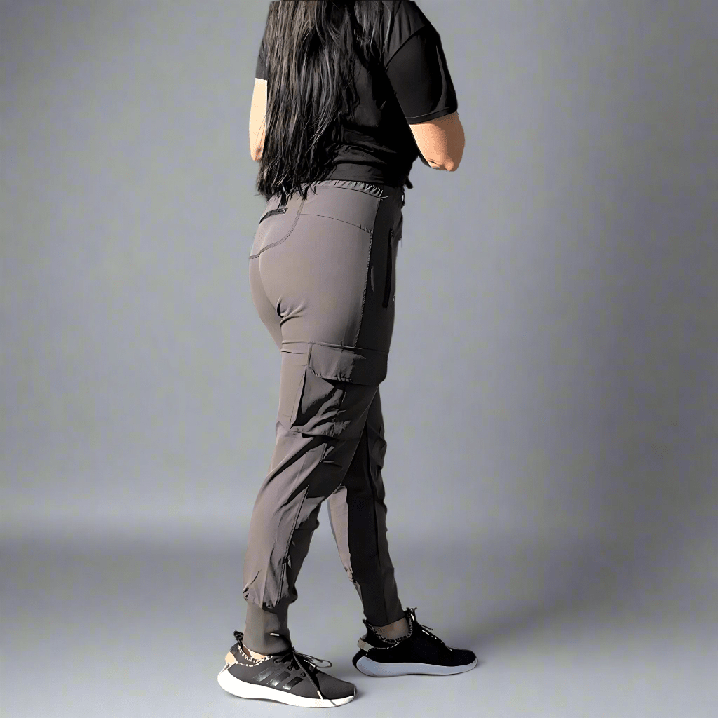 Person wearing gray cargo pants and black shoes on a plain background