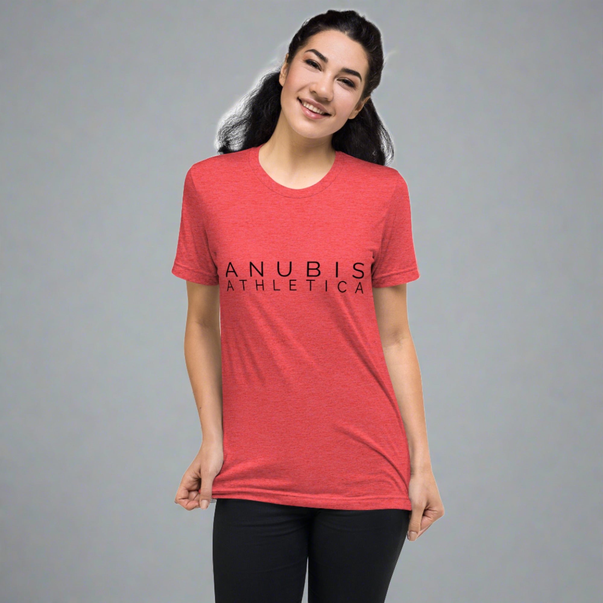 a brown haired women wearing a tee shirt with the name Anubis Athletica on the front printed in black. The shirt is the color red