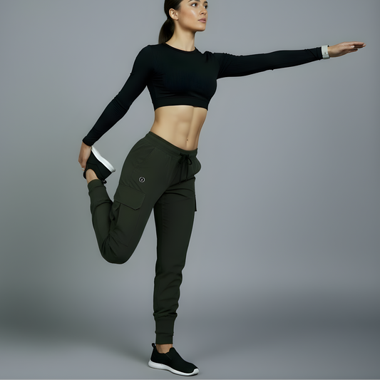Woman in black athletic top and green leggings posing against a gray background
